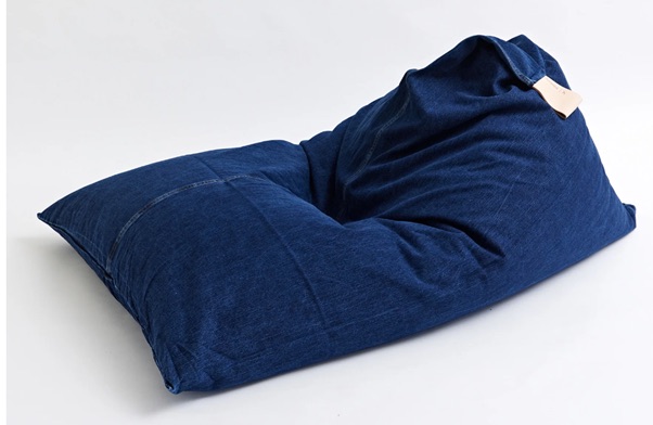 A large blue bean bag chair with a soft, slouched shape and a small beige label attached, placed on a plain white background.