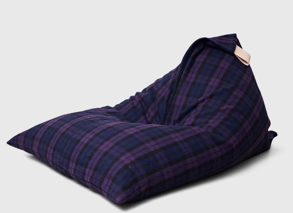 A dark blue and black checked bean bag chair with a beige handle on one corner, set against a plain light background.