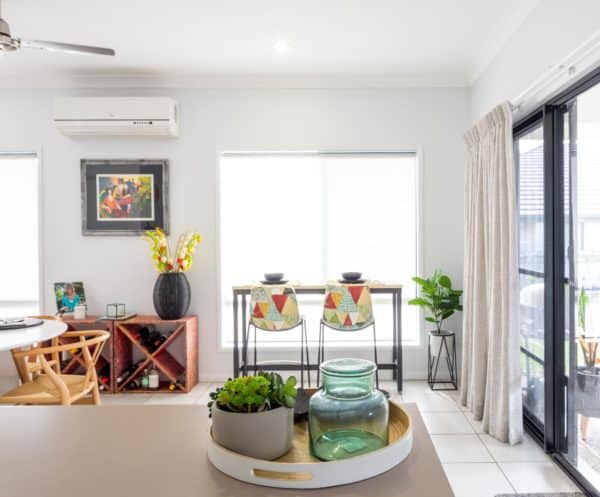 Bright modern dining area with colourful chairs, a small table set for two, indoor plants, and large windows letting in natural light.