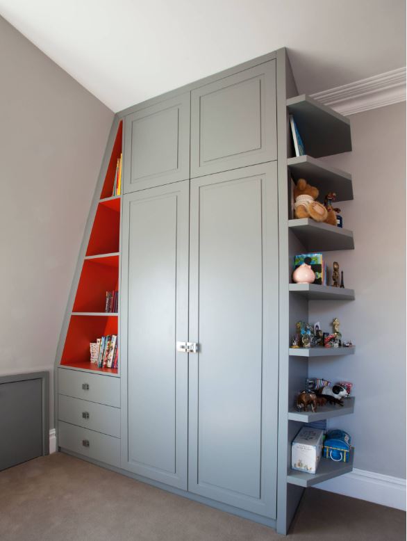 Grey built-in wardrobe with two doors, angled red shelving on the left holding books, and open shelves on the right displaying toys and collectables against a light-coloured wall.