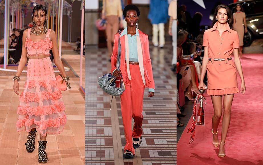 Three models walk catwalks wearing different coral-coloured outfits: a ruffled skirt set, a trouser suit with a blue blouse, and a belted mini dress, each accessorised uniquely.