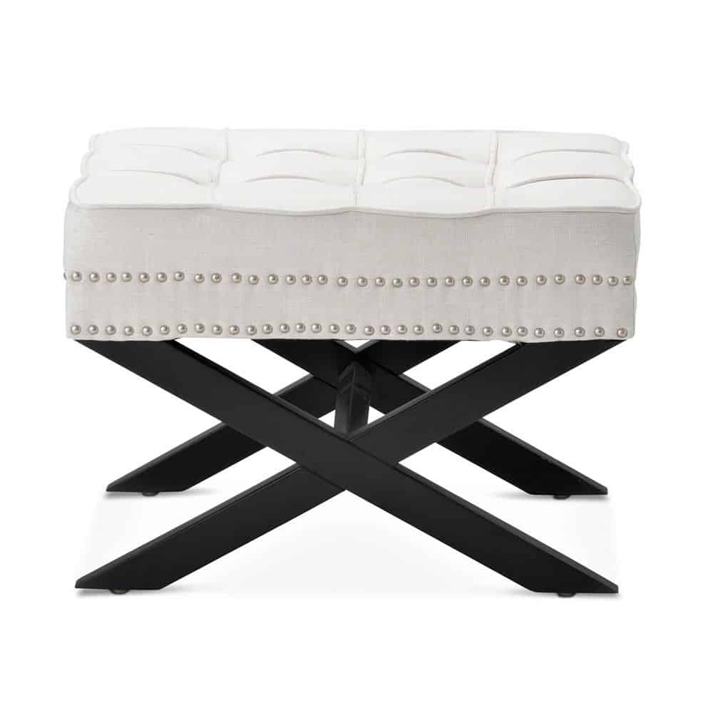 A white tufted bench with silver nailhead trim and black crossed wooden legs, shown against a plain white background.