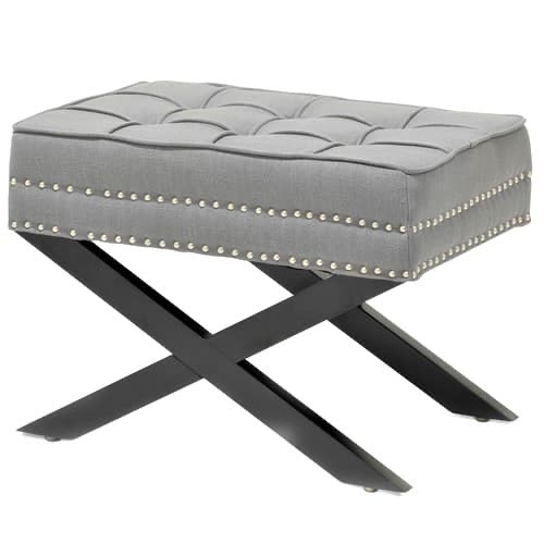 Grey tufted ottoman with silver nailhead trim and black X-shaped wooden legs, viewed from the front at a slight angle.
