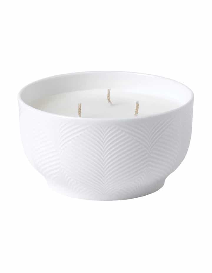 White ceramic bowl with a subtle textured pattern, filled with white wax and three unlit candle wicks.