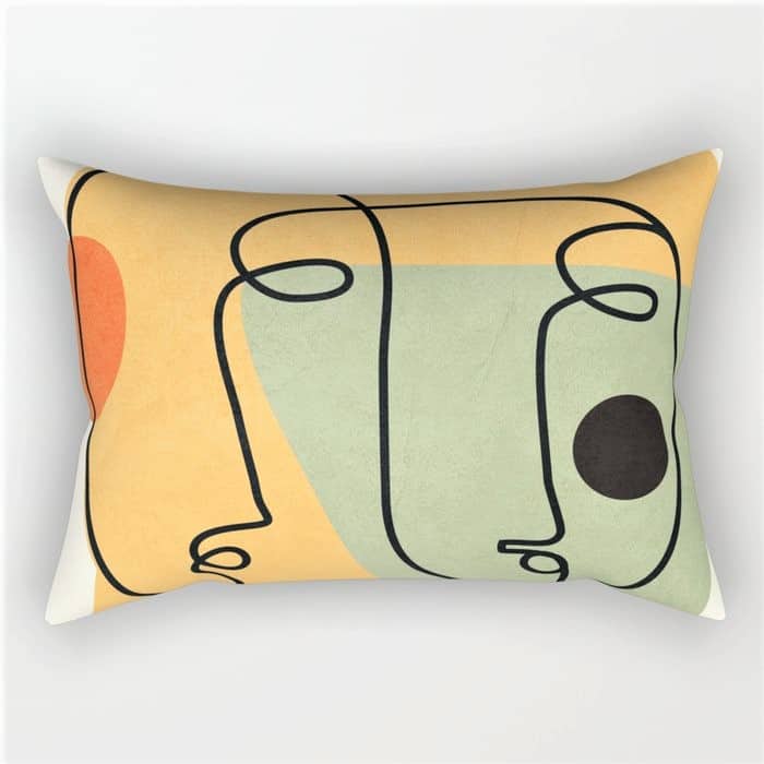 Rectangular cushion with abstract line art of faces in black over pastel green, yellow, and orange shapes.