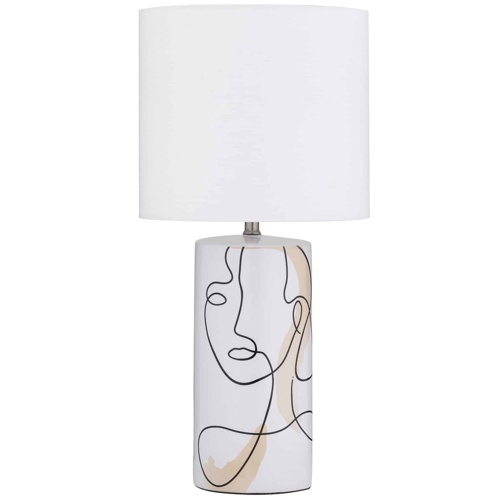 Table lamp with a white cylindrical shade and a ceramic base featuring a minimalist line drawing of a face.
