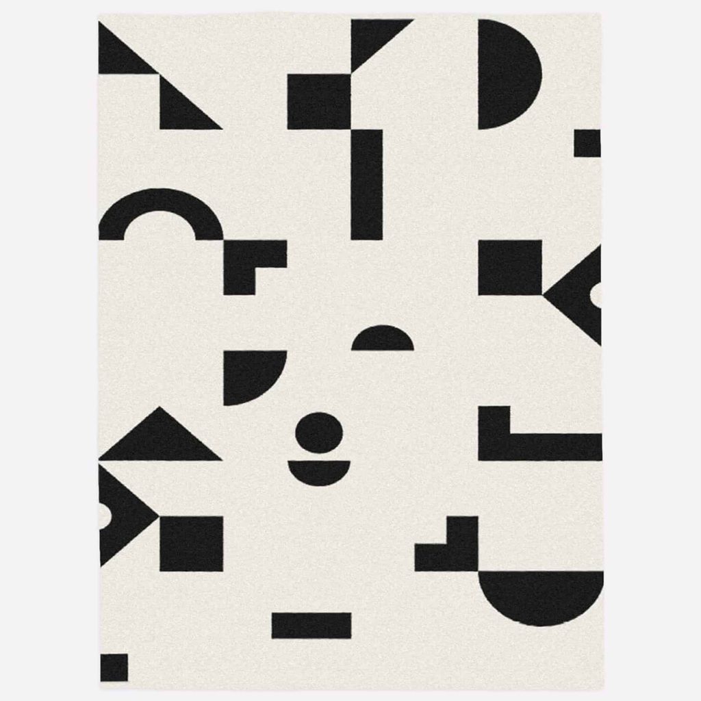 A white rectangular surface featuring an arrangement of black geometric shapes, including circles, triangles, rectangles, and semicircles, in a scattered, abstract pattern.