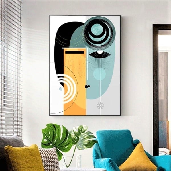 Abstract art hangs on a wall above a teal chair and a plant, with light coming in through a window with blinds.