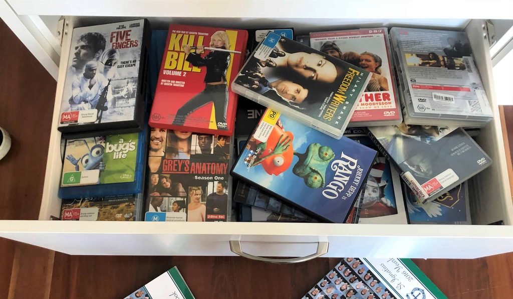 Open drawer filled with various DVD cases, including films like “Kill Bill Vol. 2,” “A Bug’s Life,” “Freedom Writers,” and TV series “Grey’s Anatomy” series one.